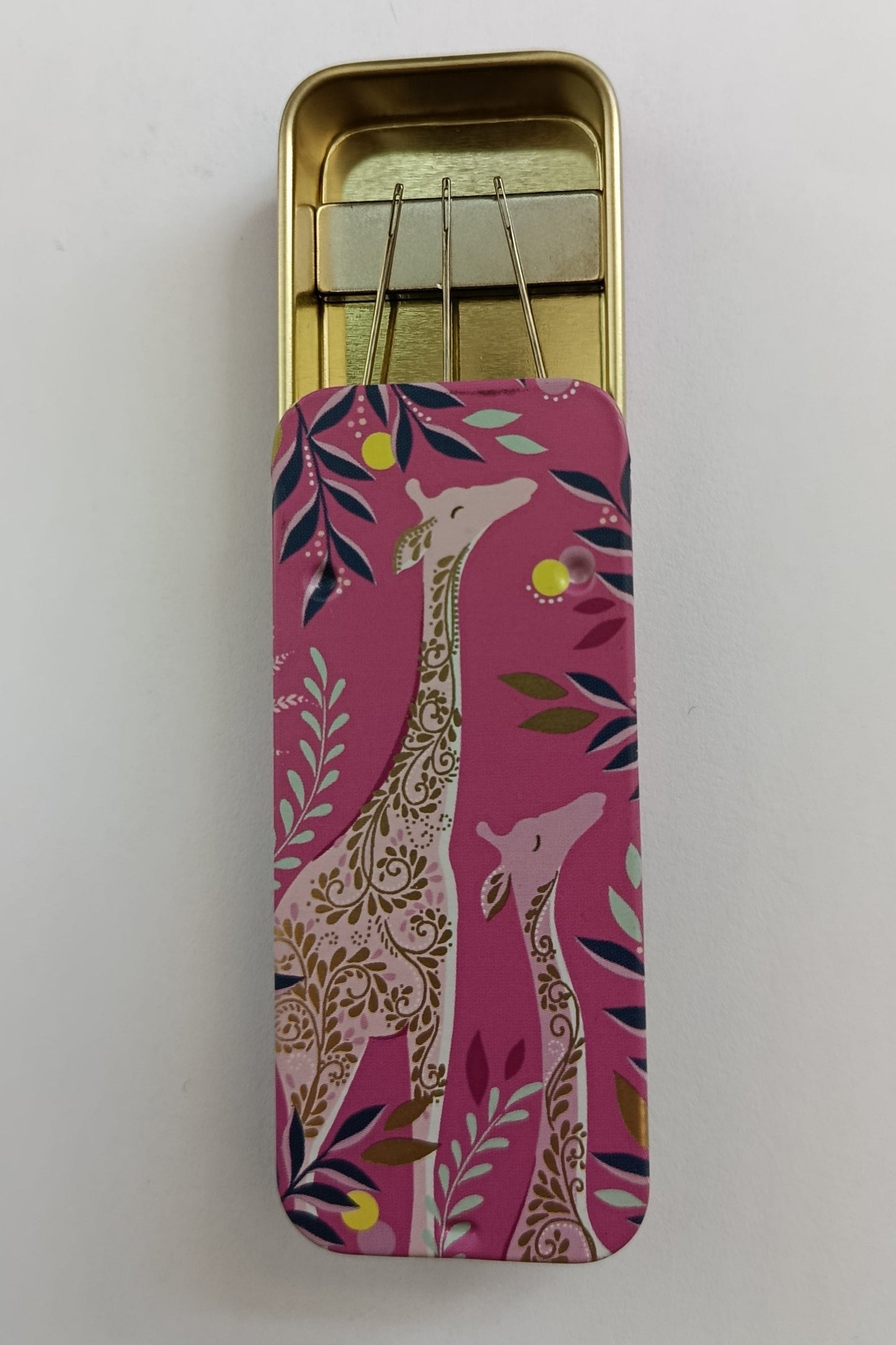 Decorative pink case with giraffe design on a white background containing a magnet to hold needles in place