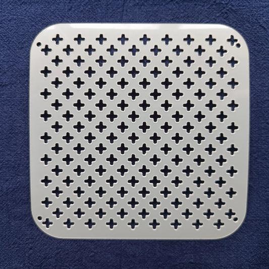 white square stencil of alternating crosses on a blue fabric background