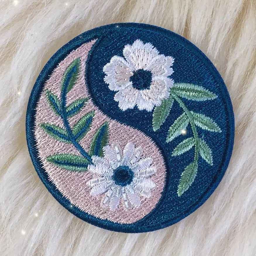 Embroidered patch with yin yang symbol and floral design on a textured surface