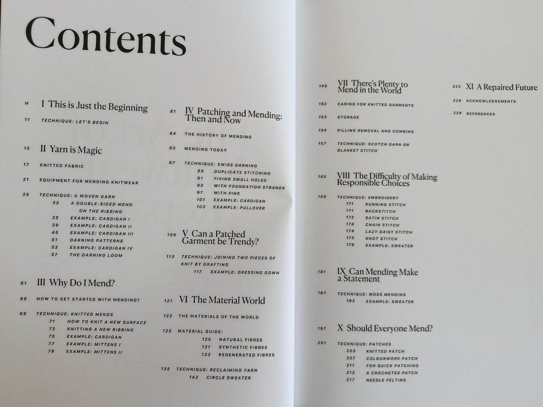 An open book spread showing printed table of contents pages with black text on white paper, photographed from above on a dark wooden surface.