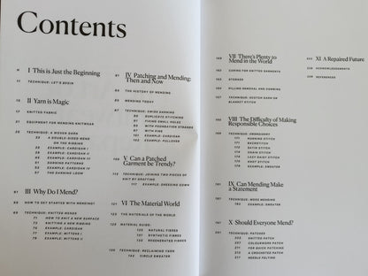 An open book spread showing printed table of contents pages with black text on white paper, photographed from above on a dark wooden surface.