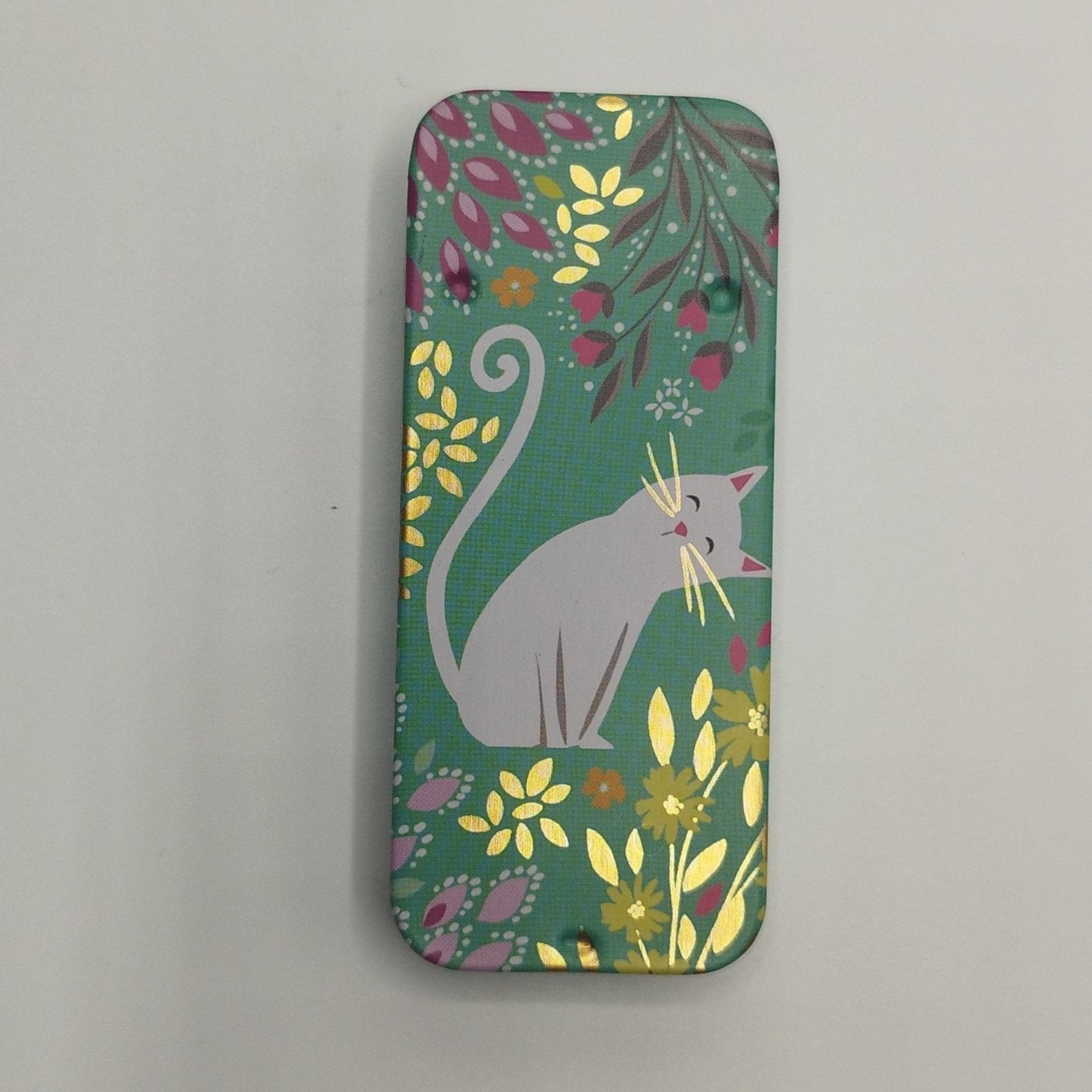 A rectangular magnetic needle tin case with a green background, featuring a illustration of a white cat among colourful flowers.