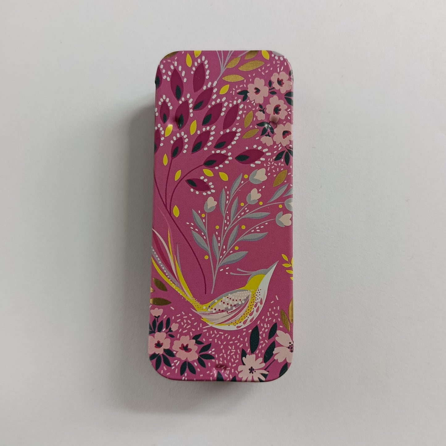 Pink slider tin with floral and bird design on a white background