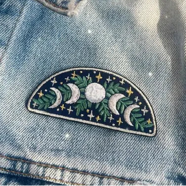 Denim jacket with a embroidered patch featuring moons and stars on a light background