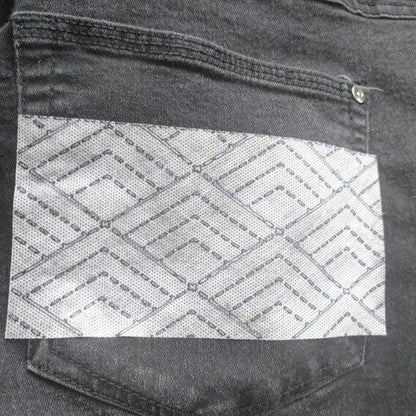 A rectangular slice of the pyramid design stuck on a black denim pocket.