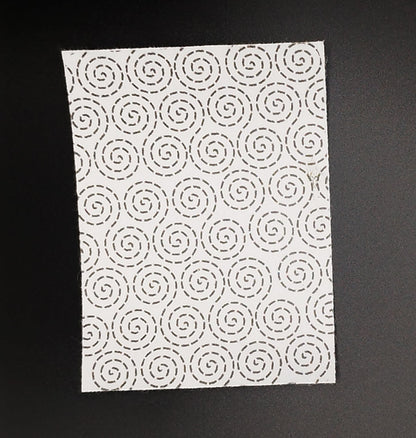 A rectangular sashiko pattern on a black background. The pattern has a swirling dashed line design.