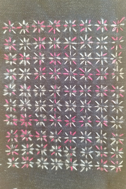 Resulting pink and white stitching of the previous starburst sashiko design on a dark denim background, with a repeated crosses/stars design. It is 6 repeats wide and 8 repeats tall. 