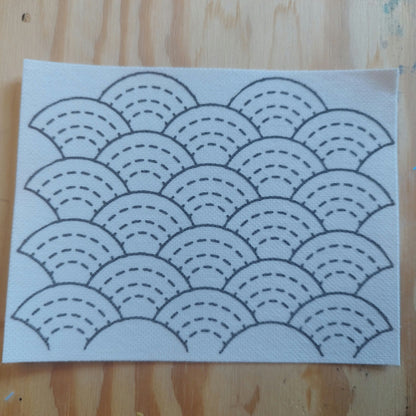 Rectangular Sashiko Stacking Rainbow Design on a light wood background. Each Rainbow has 3 rows of dashed lines, and a solid top line. The pattern is approximately 3 rainbows wide and 4 rainbows tall. 